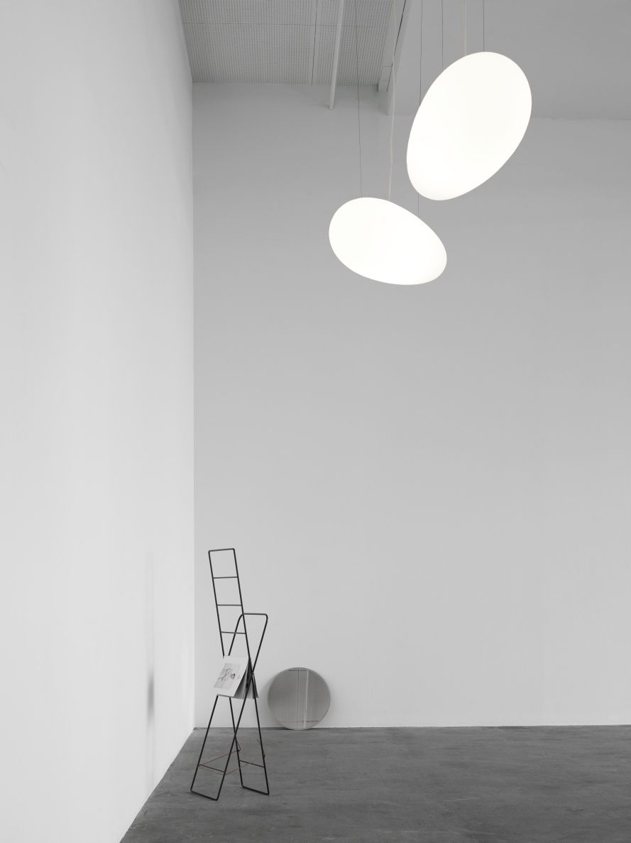 Zwei moderne Avion Pendelleuchten von Fritz Hansen in einem minimalistischen Raum mit Magazinhalter.