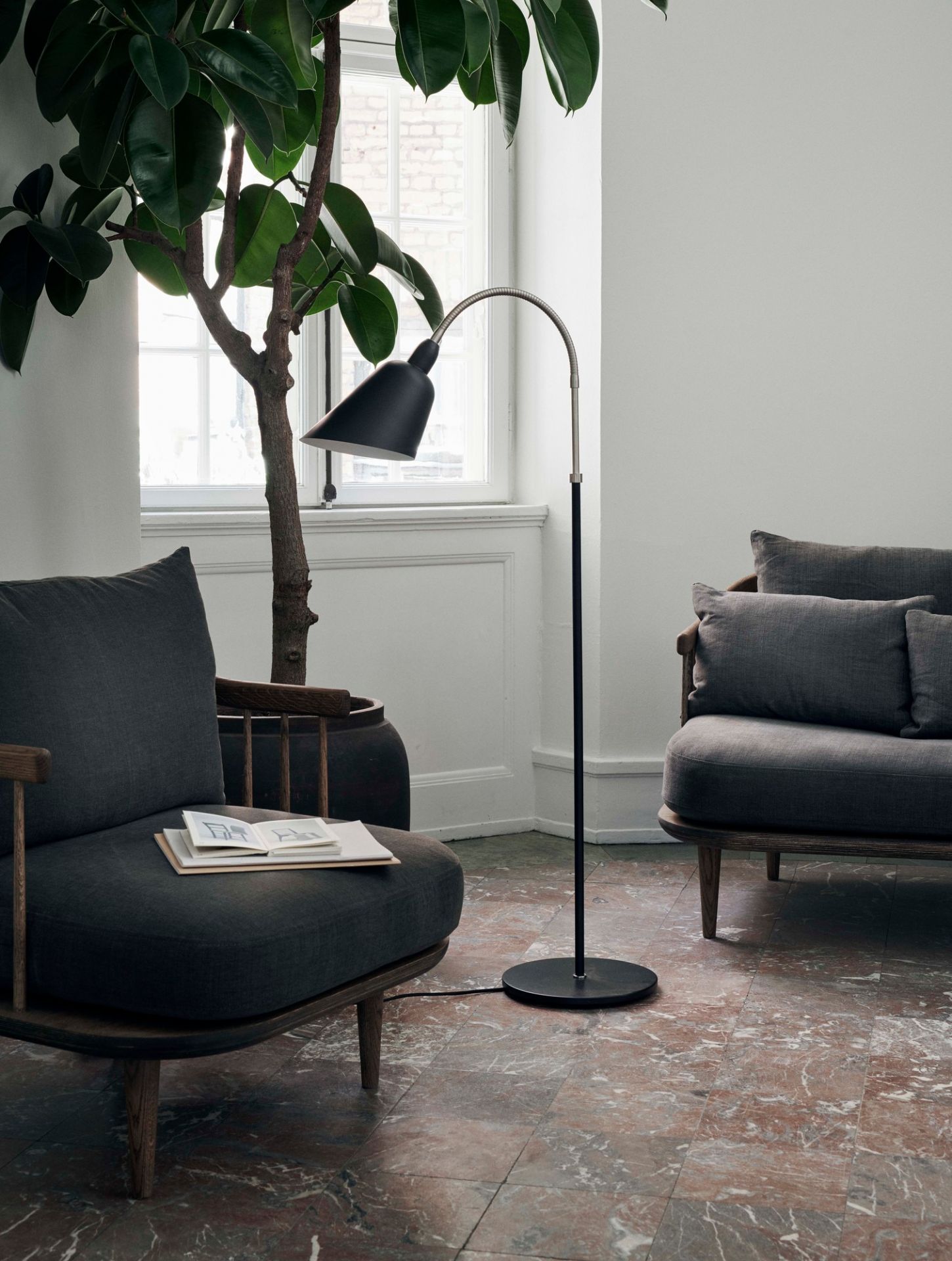 Fly Lounge Sessel von AndTradition: Grauer Sessel mit Holzelementen und passendem Sofa im Wohnzimmer.