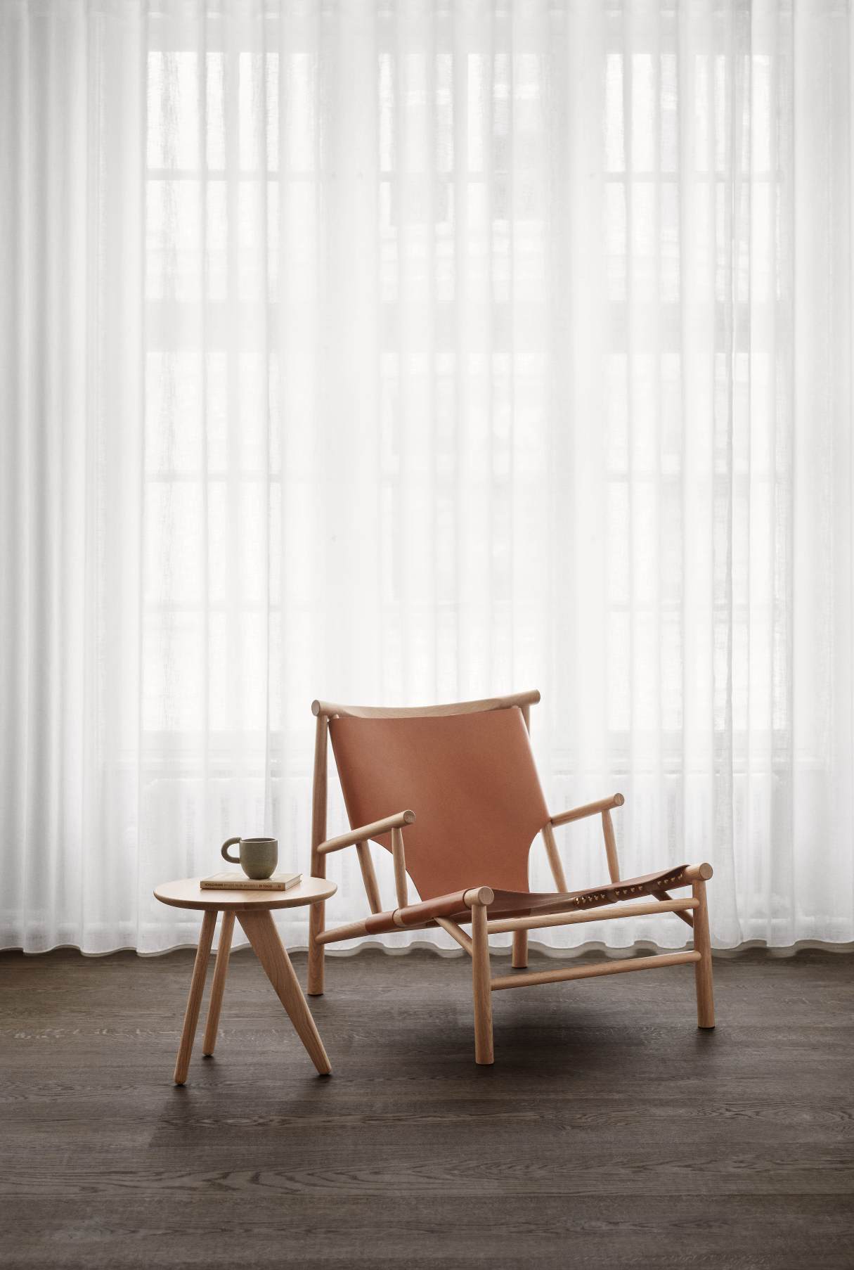 NORR11 Samurai Lounge Chair Sessel aus hellem Holz und braunem Leder vor weißem Vorhang.