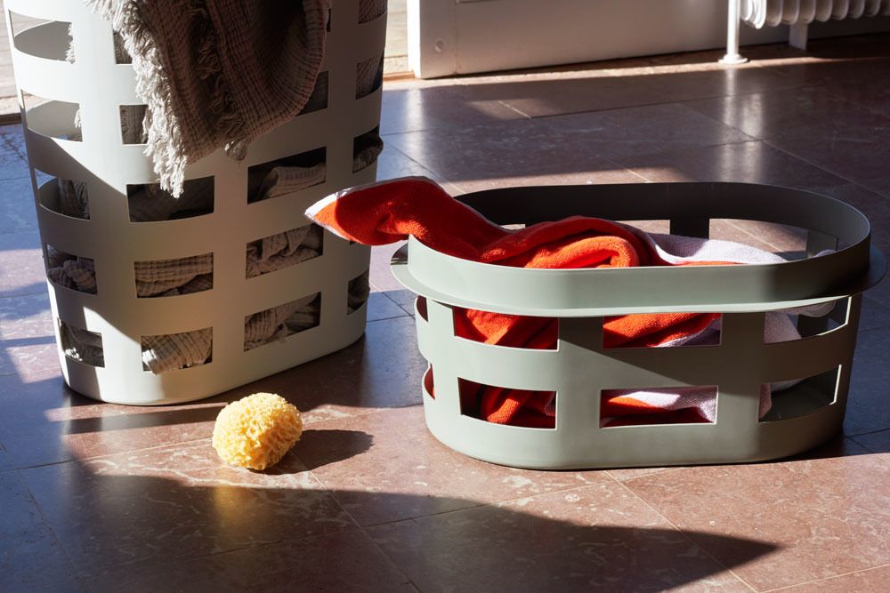 Zwei Hay Laundry Basket Wäschekörbe, einer gelb, gefüllt mit Wäsche, auf einem gefliesten Boden.