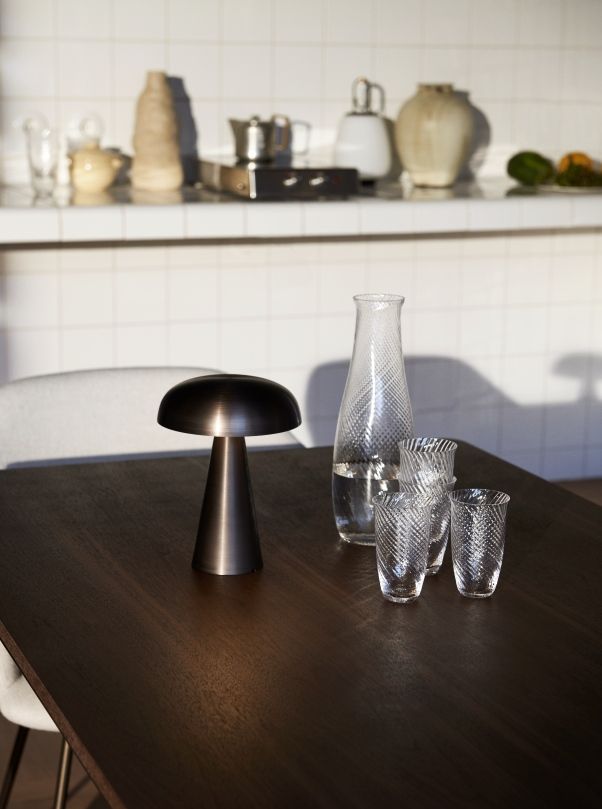 AndTradition Drip Table HW58 aus dunklem Holz mit Lampe, Gläsern und Wasserkaraffe im modernen Esszimmer.