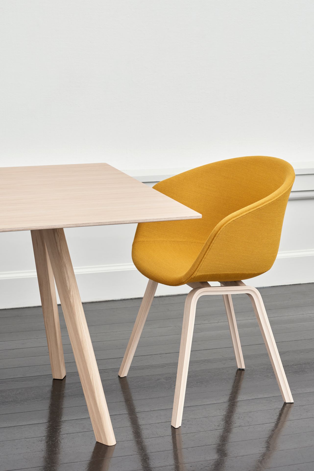 Gelber About A Chair AAC23 Stuhl von Hay mit Vollpolsterung und hellem Holzgestell am Esstisch.