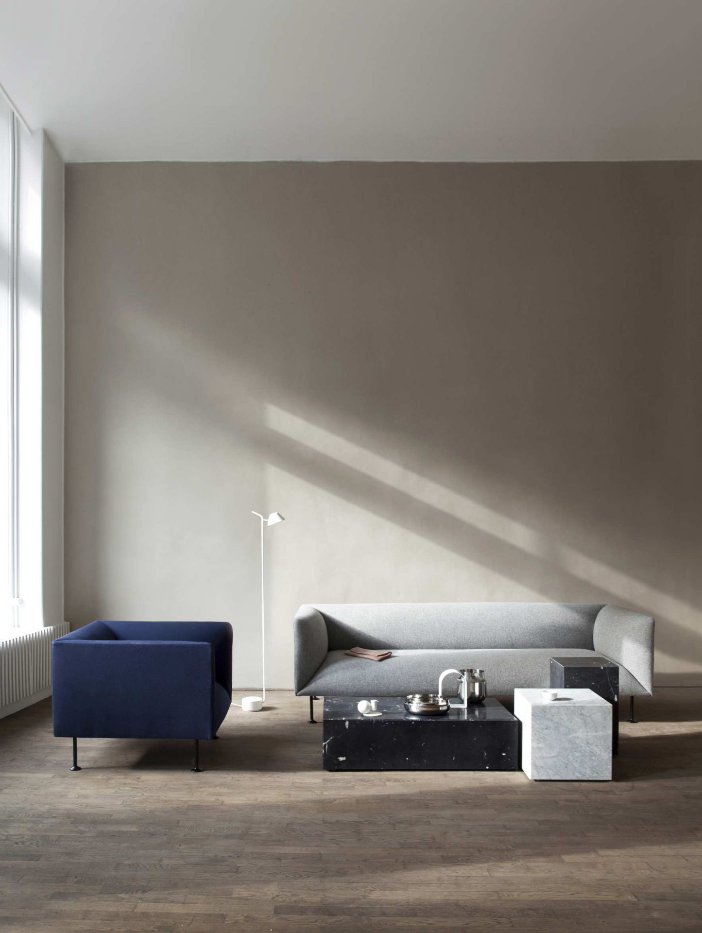 Audo Copenhagen Plinth Tisch Konfiguration mit Marmor Couchtisch und grauem Sofa im modernen Wohnzimmer.