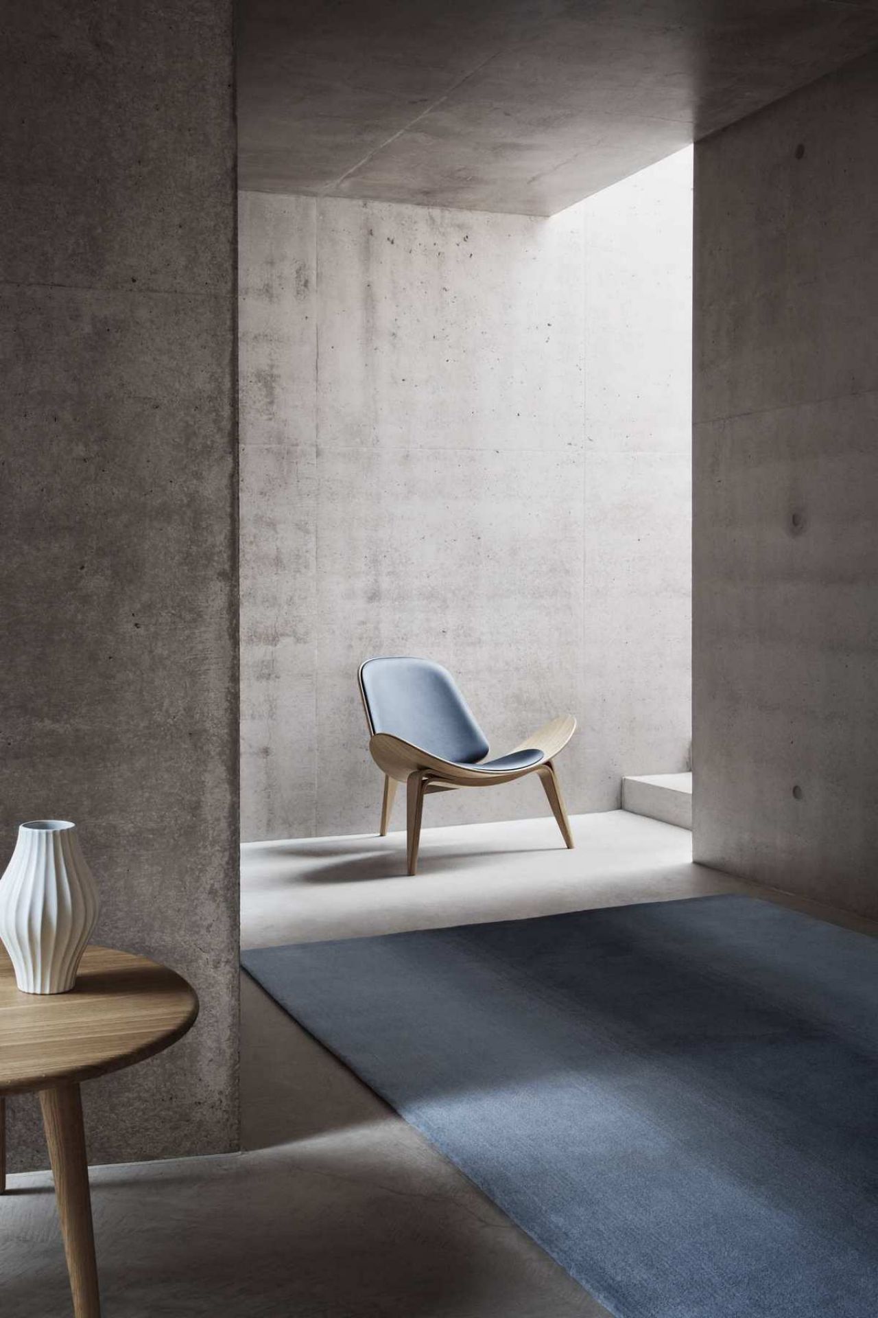 CH07 Shell Chair Stuhl von Carl Hansen mit blauer Polsterung und Holzgestell im modernen Raum.