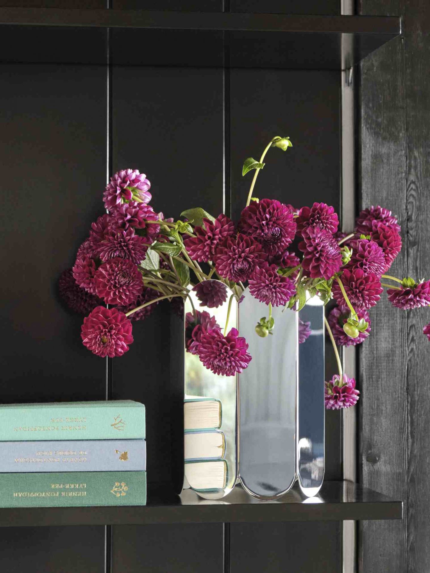 Nahaufnahme der Arcs Vase L Mirror von Hay mit lila Dahlien auf einem schwarzen Regal.