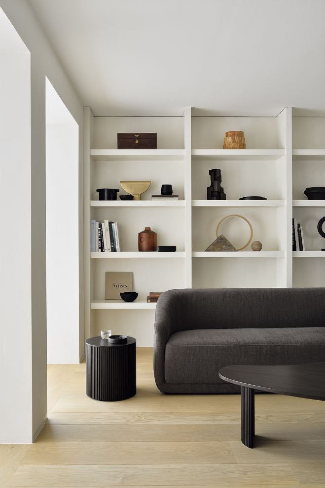 Dunkelbrauner Ethnicraft Roller Max Beistelltisch rund im modernen Wohnzimmer neben Sofa und Regal.