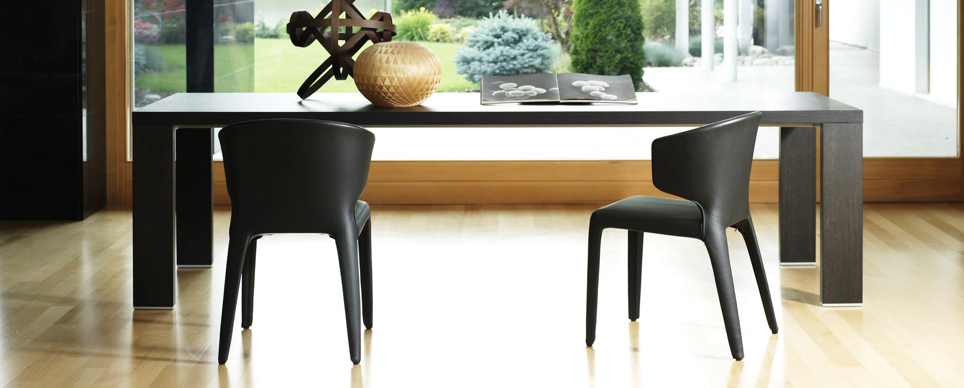 Zwei schwarze Cassina Hola Armlehnstühle aus Leder am Esstisch, modernes Möbeldesign für Esszimmer.
