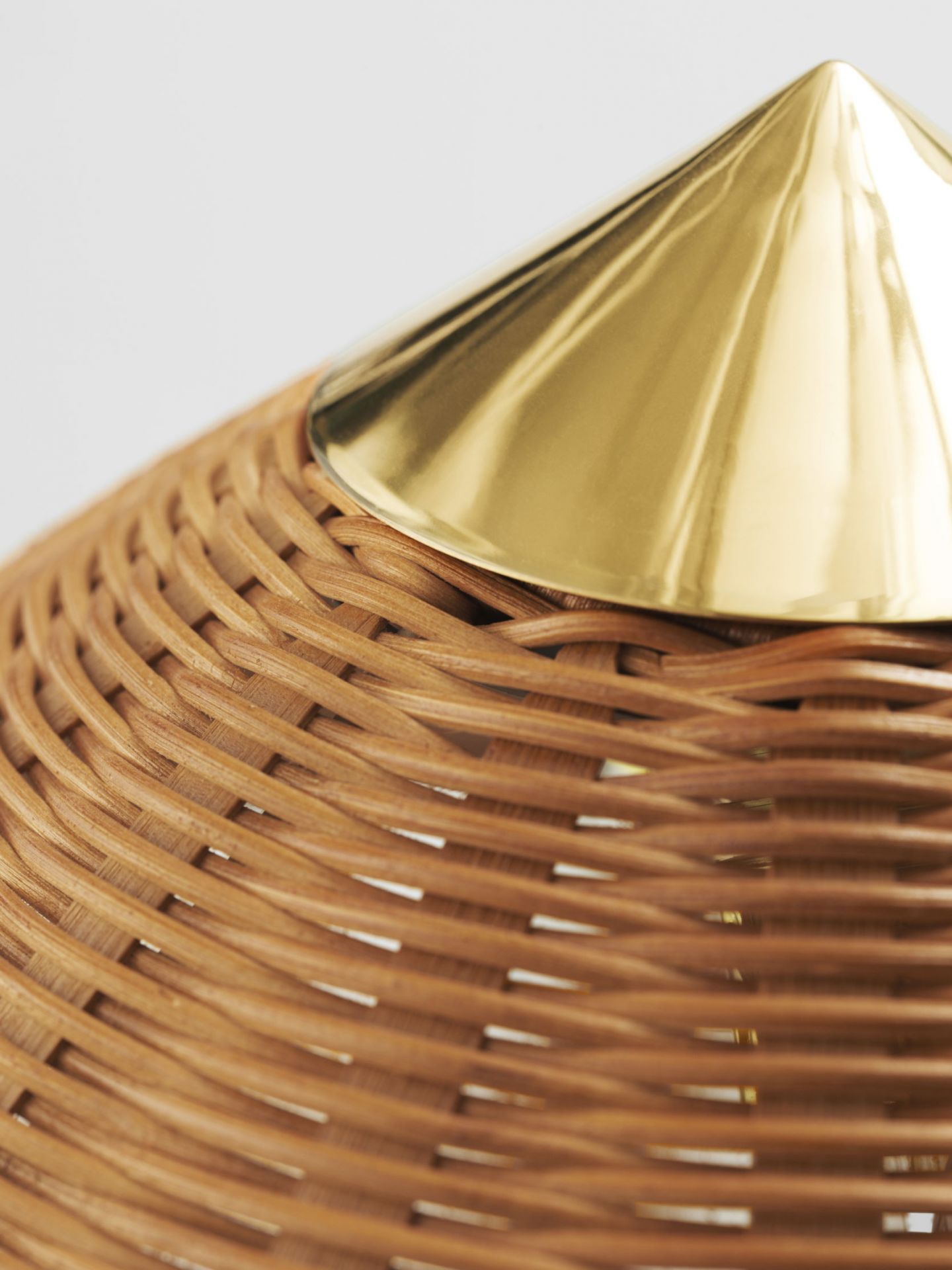 Detailaufnahme der Gubi 9602 Stehleuchte: Rattan-Schirm mit goldfarbenem Kegelaufsatz. Design Lampe für Wohnzimmer.