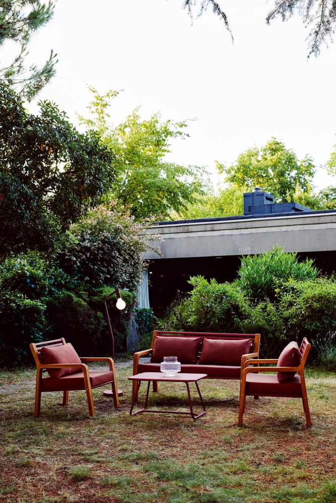 Fermob Somerset Sessel und Sofa Outdoor-Lounge-Set mit Tisch und Lampe im Garten.