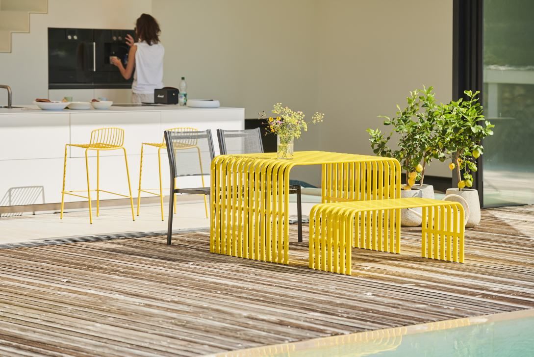 Gelbe Campus Bank von Jan Kurtz für den Außenbereich mit Tisch und Sitzbank auf Holzterrasse.