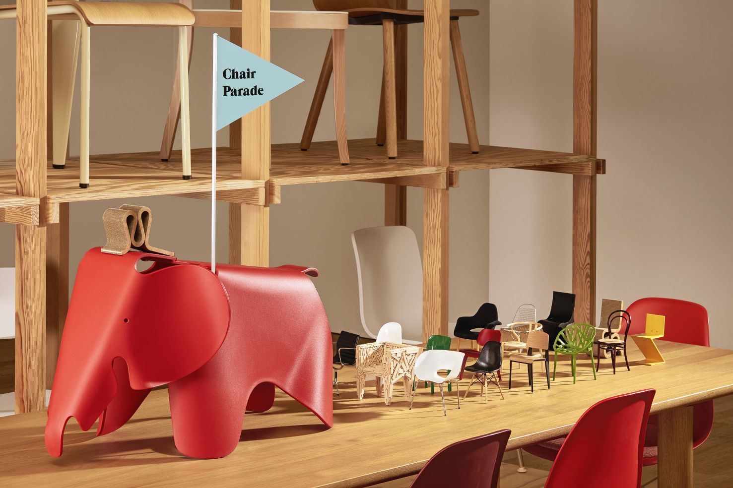 Produktfoto: Vitra Miniatur Stuhl Kollektion, inklusive LCW Stuhl, auf einem Holztisch arrangiert.