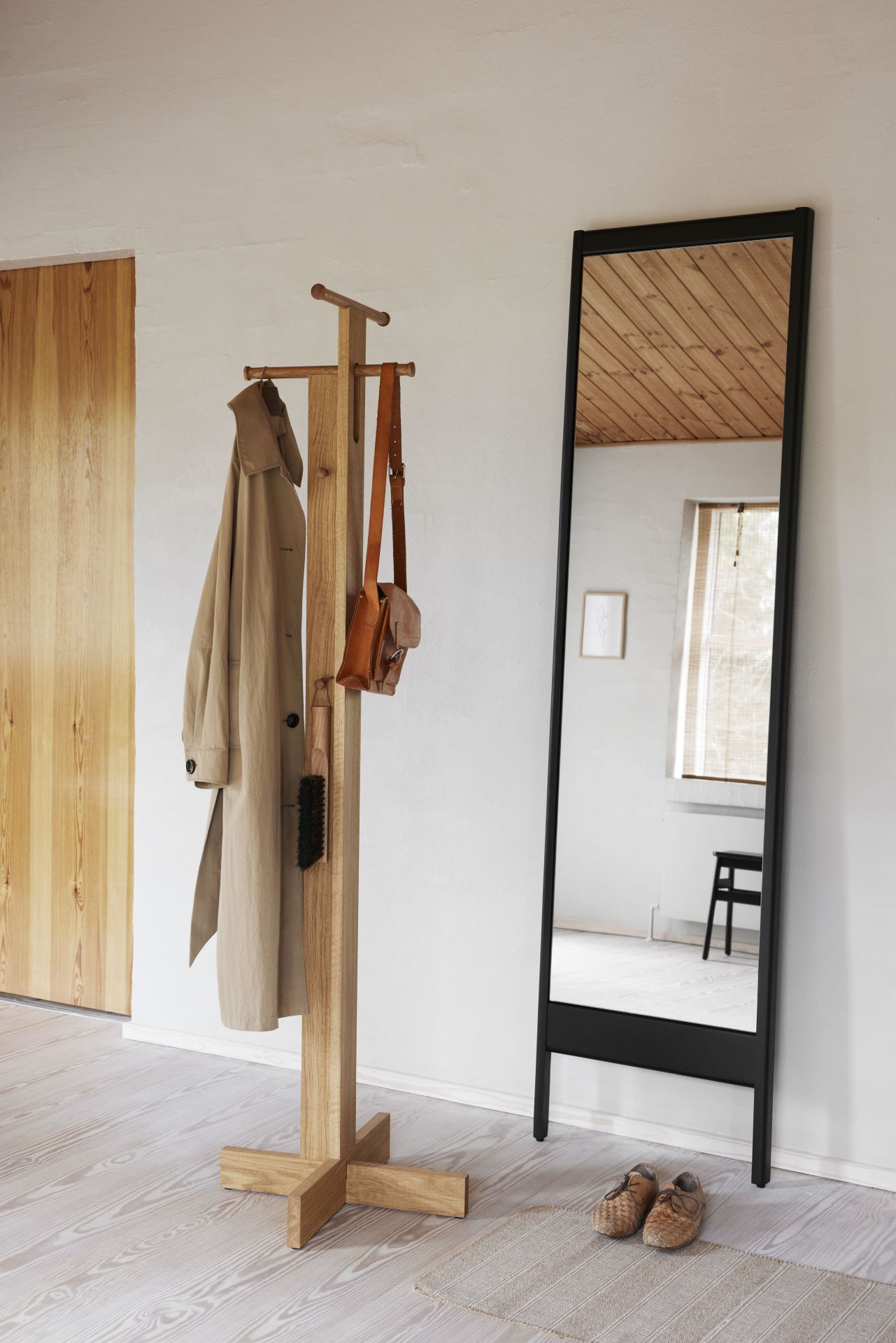 Foyer Garderobenständer aus Holz mit Mantel, Tasche und Schuhanzieher, neben einem großen Spiegel im Flur.