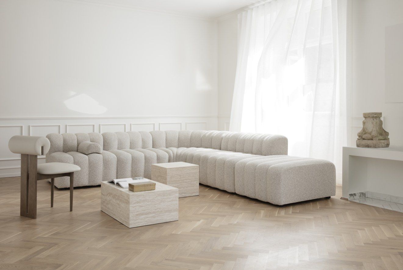 Heller Wohnraum mit Hippo Stuhl von NORR11, modularem Sofa, Couchtischen aus Travertin und Parkettboden.