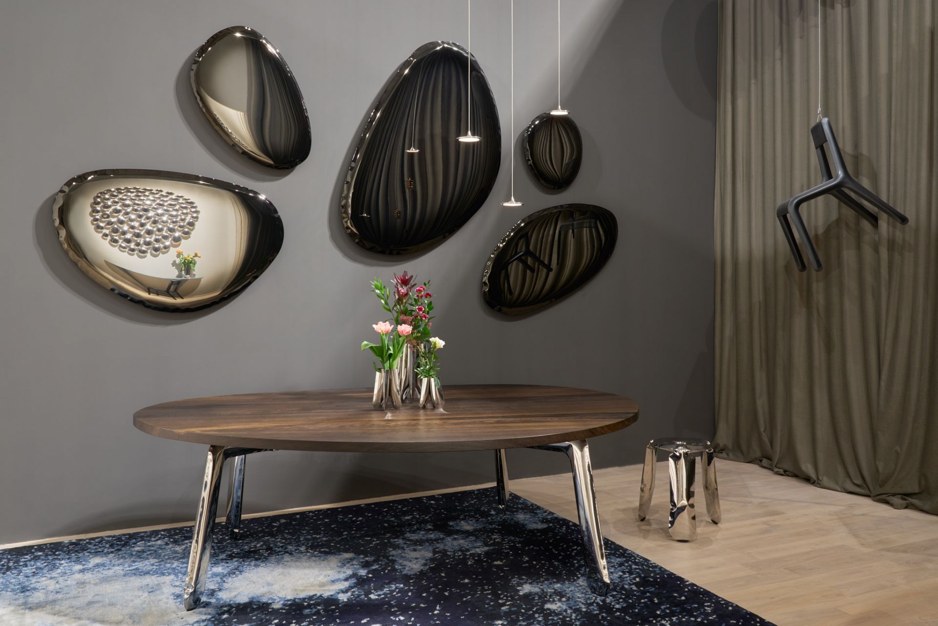 Tafla Spiegel "Dark Matter" von Zieta mit organischen Formen an grauer Wand über Esstisch.