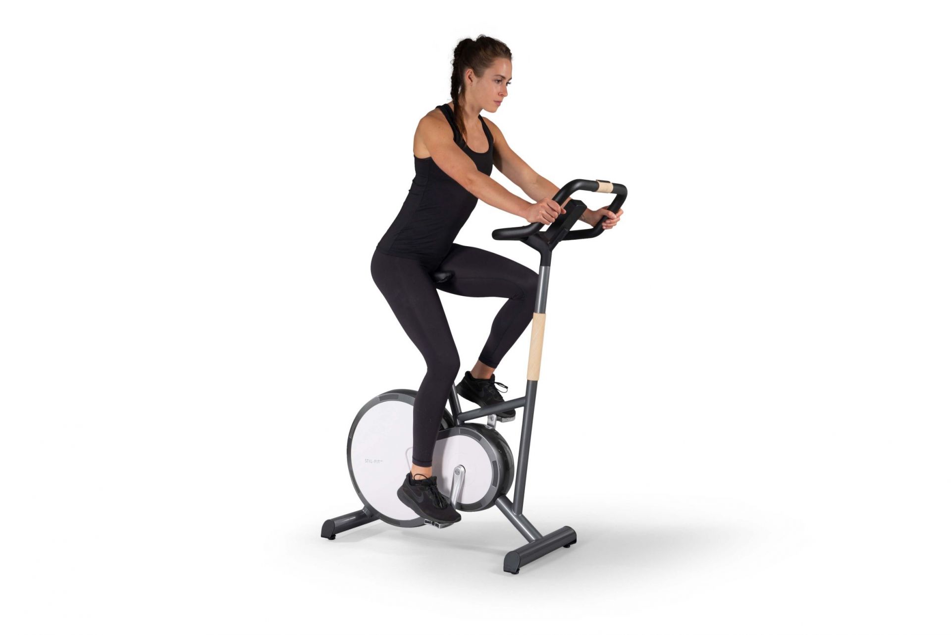 Frau trainiert auf dem Stil-Fit Ergometer in Walnuss-Schwarz. Heimtrainer für Fitness und Cardiotraining.