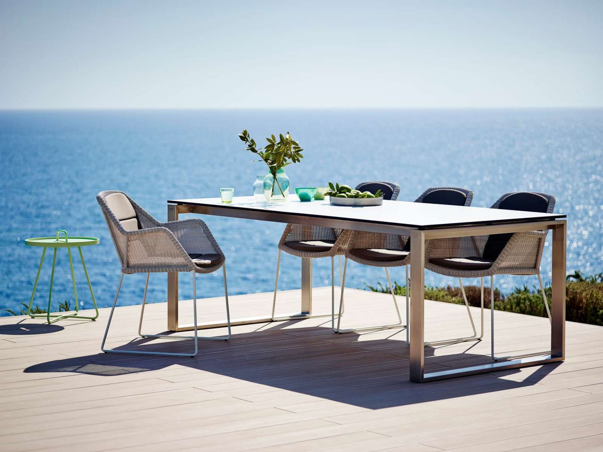 Breeze Outdoor Stuhl von Cane-Line mit Kufengestell, 2er Set, auf einer Terrasse am Meer.