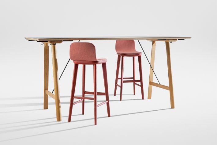Aeon Barstool: Vollgepolsterter Barhocker in Rot vor einem Bartisch mit hellem Holzgestell.