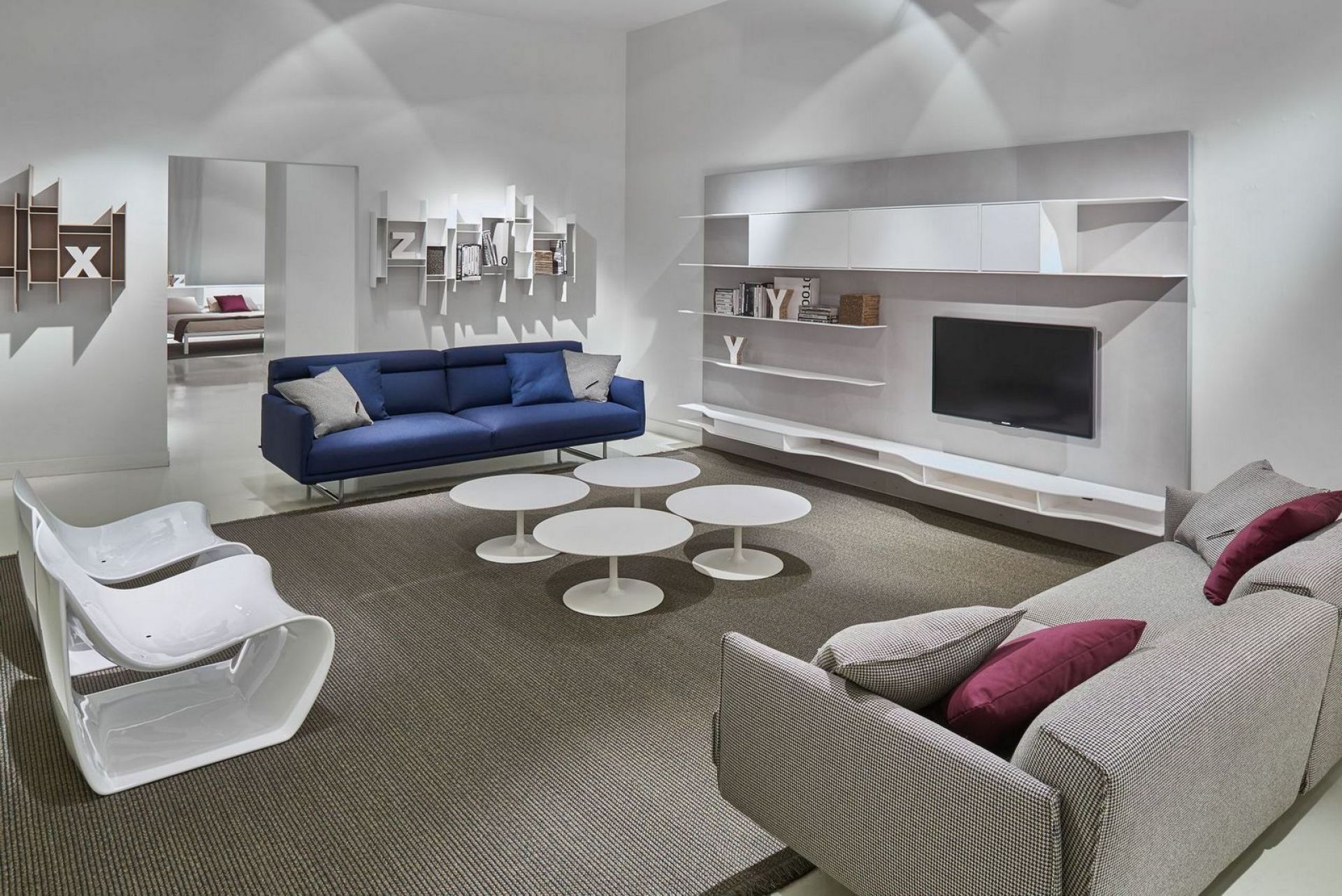 Wohnzimmer mit blauem Sofa und vier weißen Flow Low Table Couchtischen von MDF Italia.