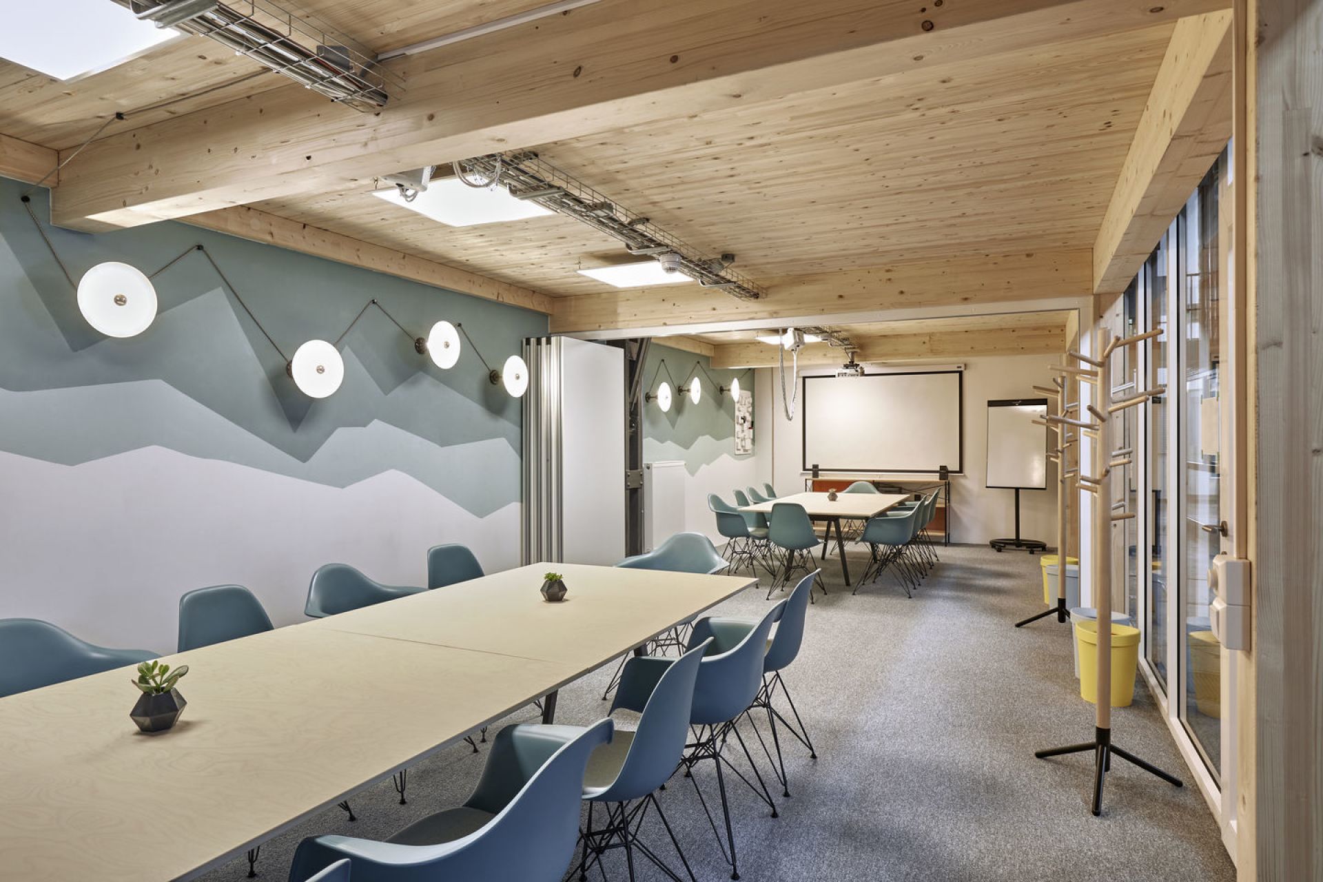 Konferenzraum mit langem Holztisch und blauen Eames Plastic Arm Chairs DAR Stühlen von Vitra.