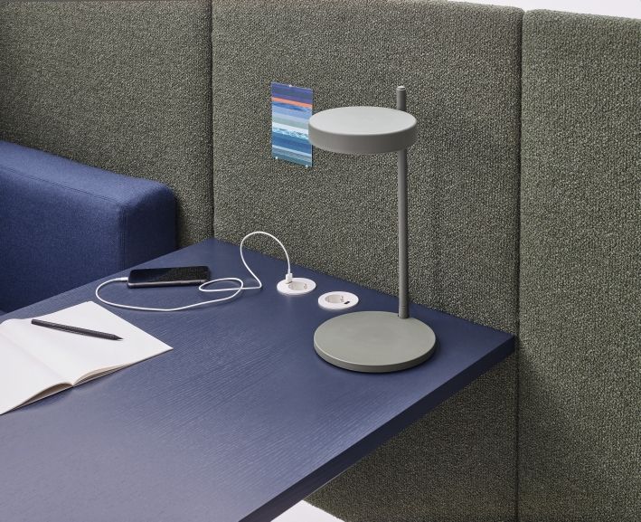 Detailaufnahme des Cor Floater Sofas mit integriertem Tisch, Lampe, Steckdosen, Notizbuch, Stift und Smartphone.
