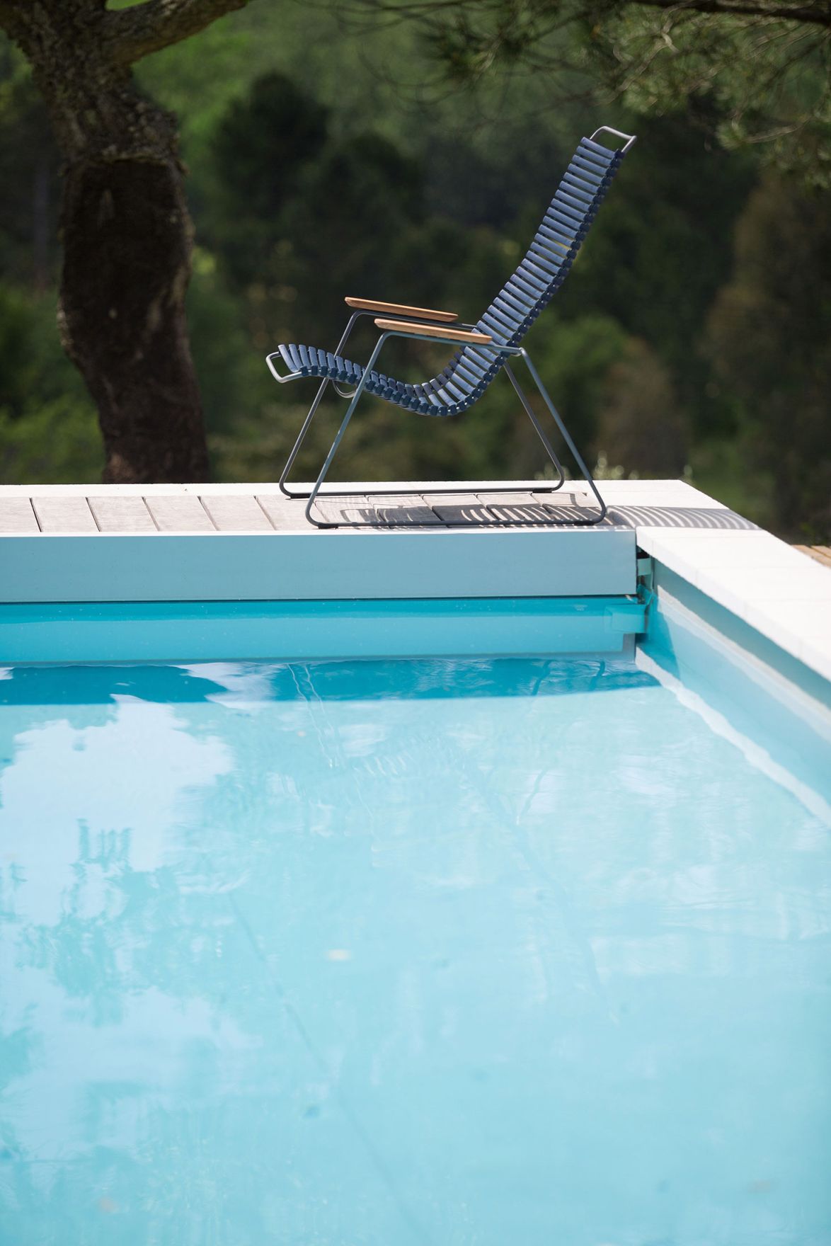 Blauer Click Lounge Chair von Houe neben einem Pool im Freien.