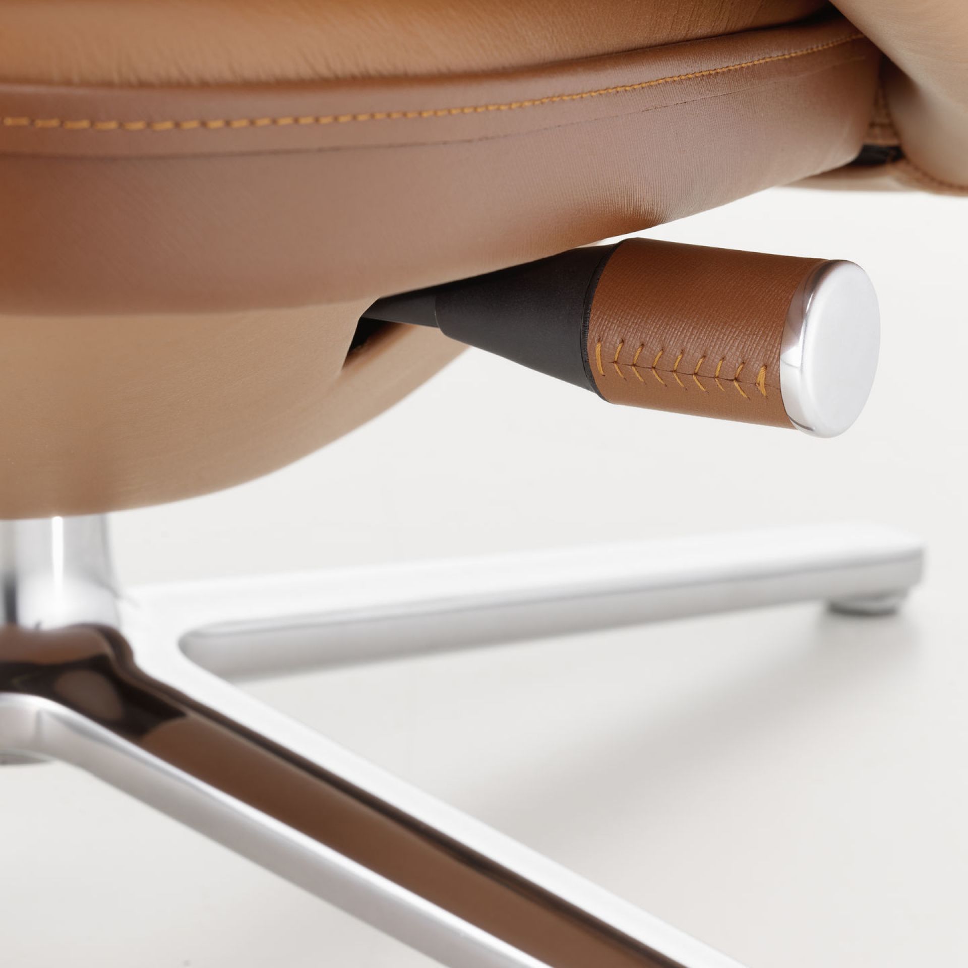 Detailaufnahme: Verstellhebel und Fußkreuz des Vitra Grand Relax Sessels mit braunem Lederbezug.
