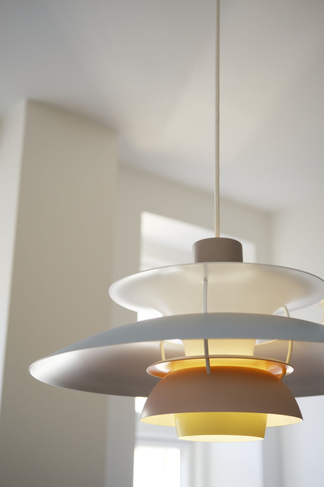 Nahaufnahme der PH 5 Pendelleuchte von Louis Poulsen in Weiß- und Gelbtönen, modernes Design.