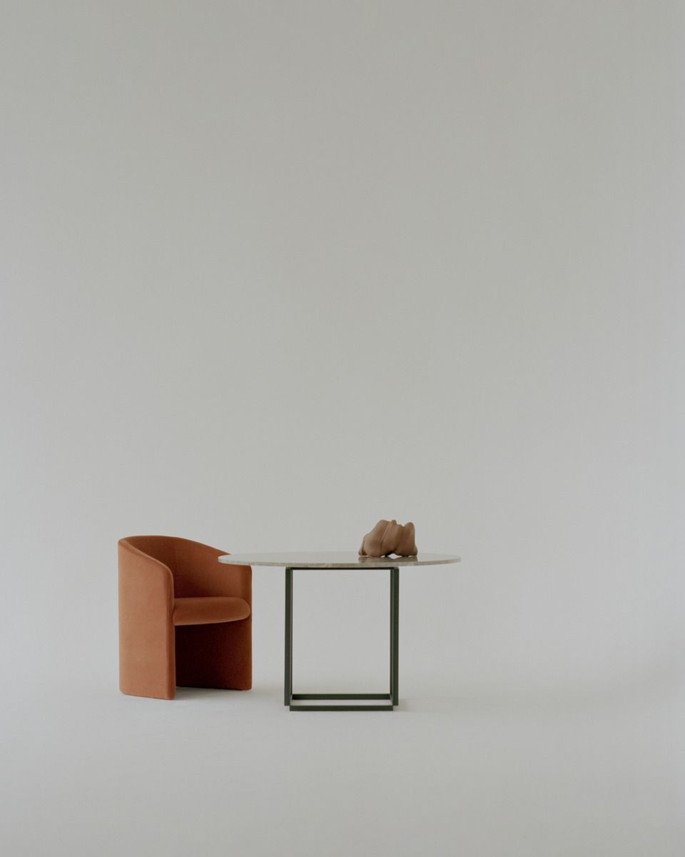 Covent Club Chair Sessel von New Works in Orange neben einem runden Tisch.