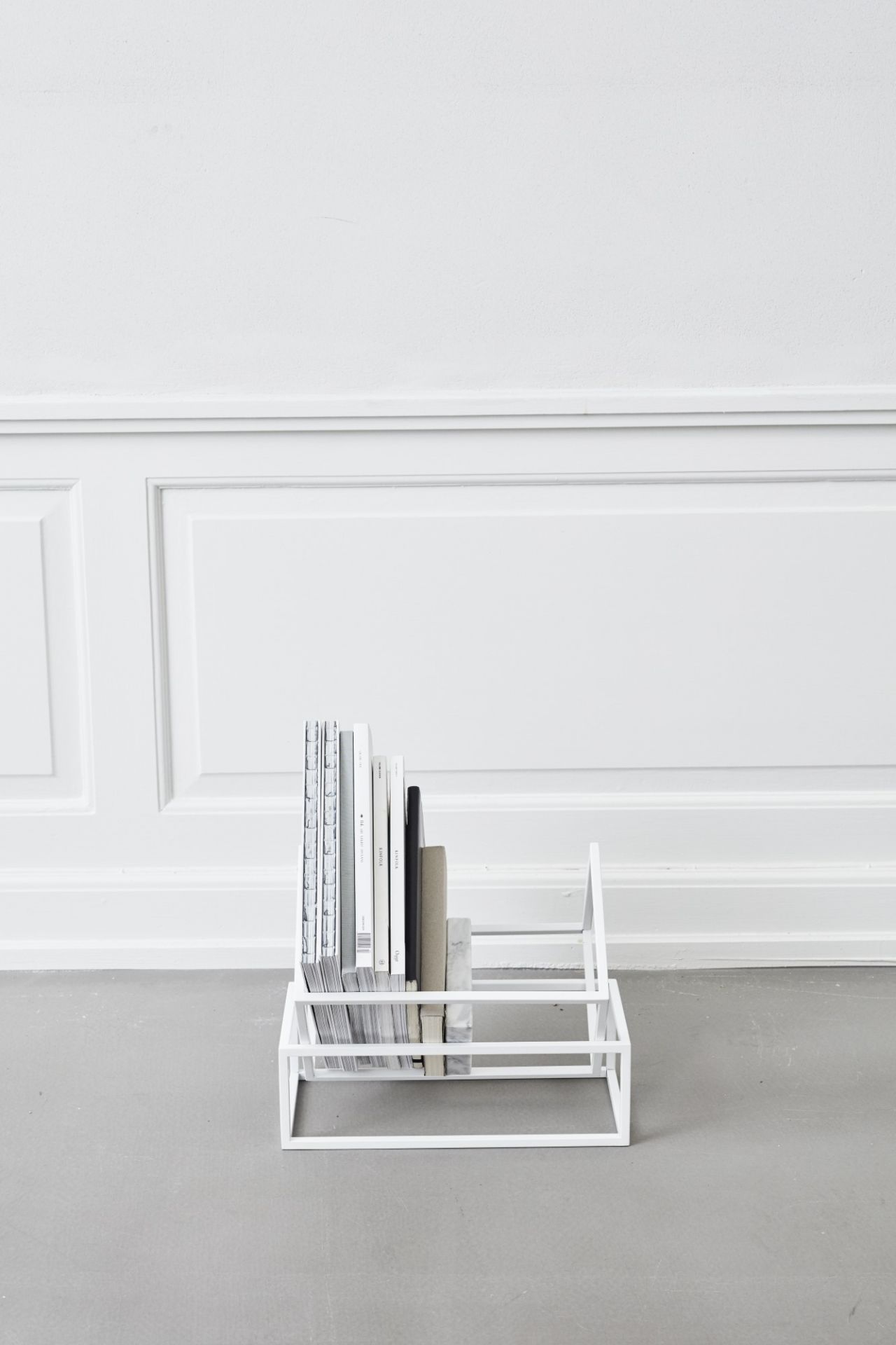 Weißer Book Keeper Bücherhalter von Kristina Dam mit Büchern auf grauem Boden.