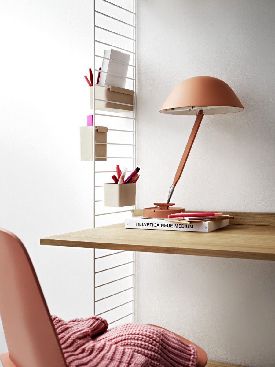 String Furniture Arbeitsplatz mit Regalsystem, Schreibtisch, Lampe und Stuhl in sanften Farben.