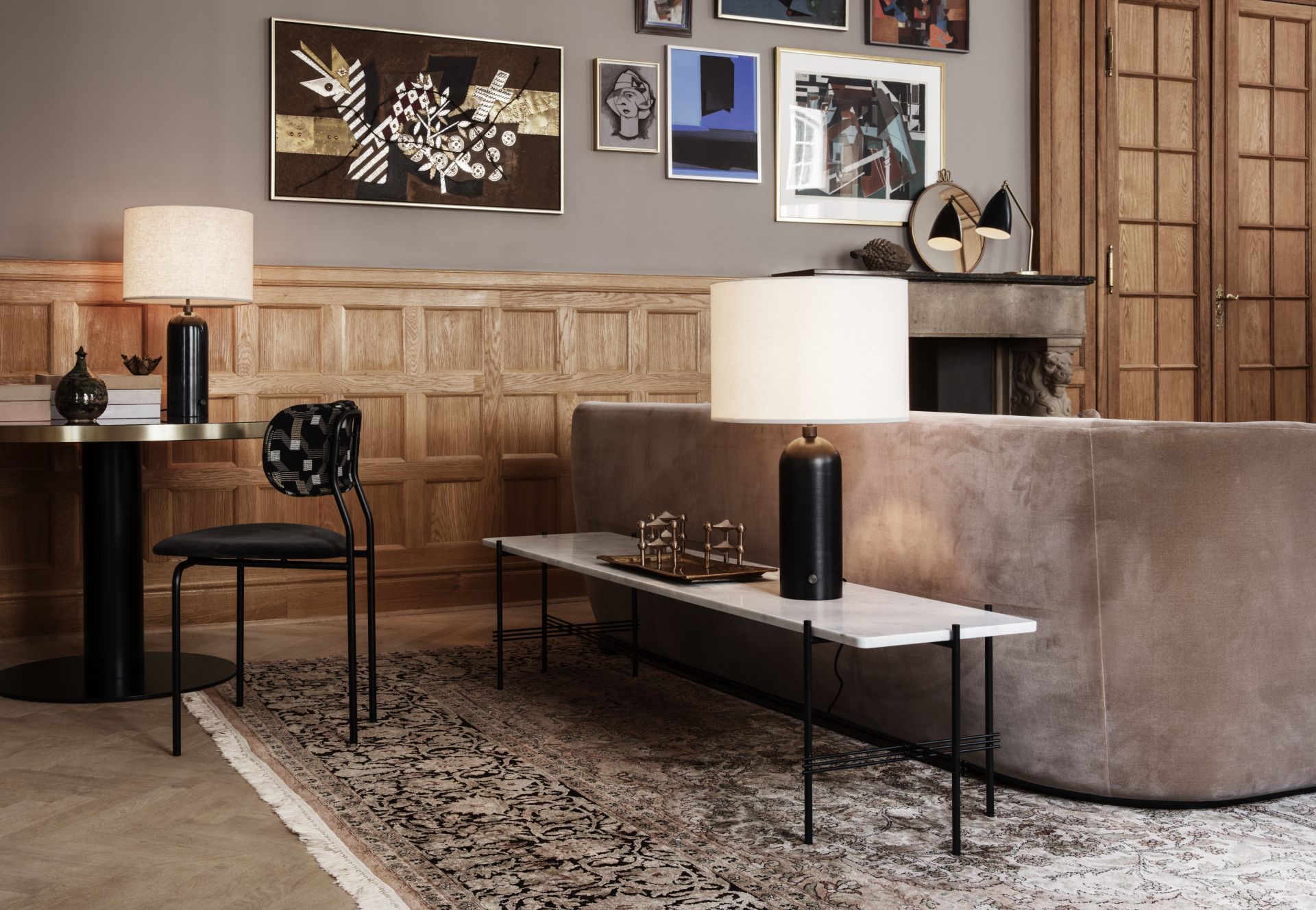 Elegante Wohnzimmer-Szene mit Gräshoppa Tischleuchte von Gubi, die warmes Licht auf einem Marmortisch spendet.