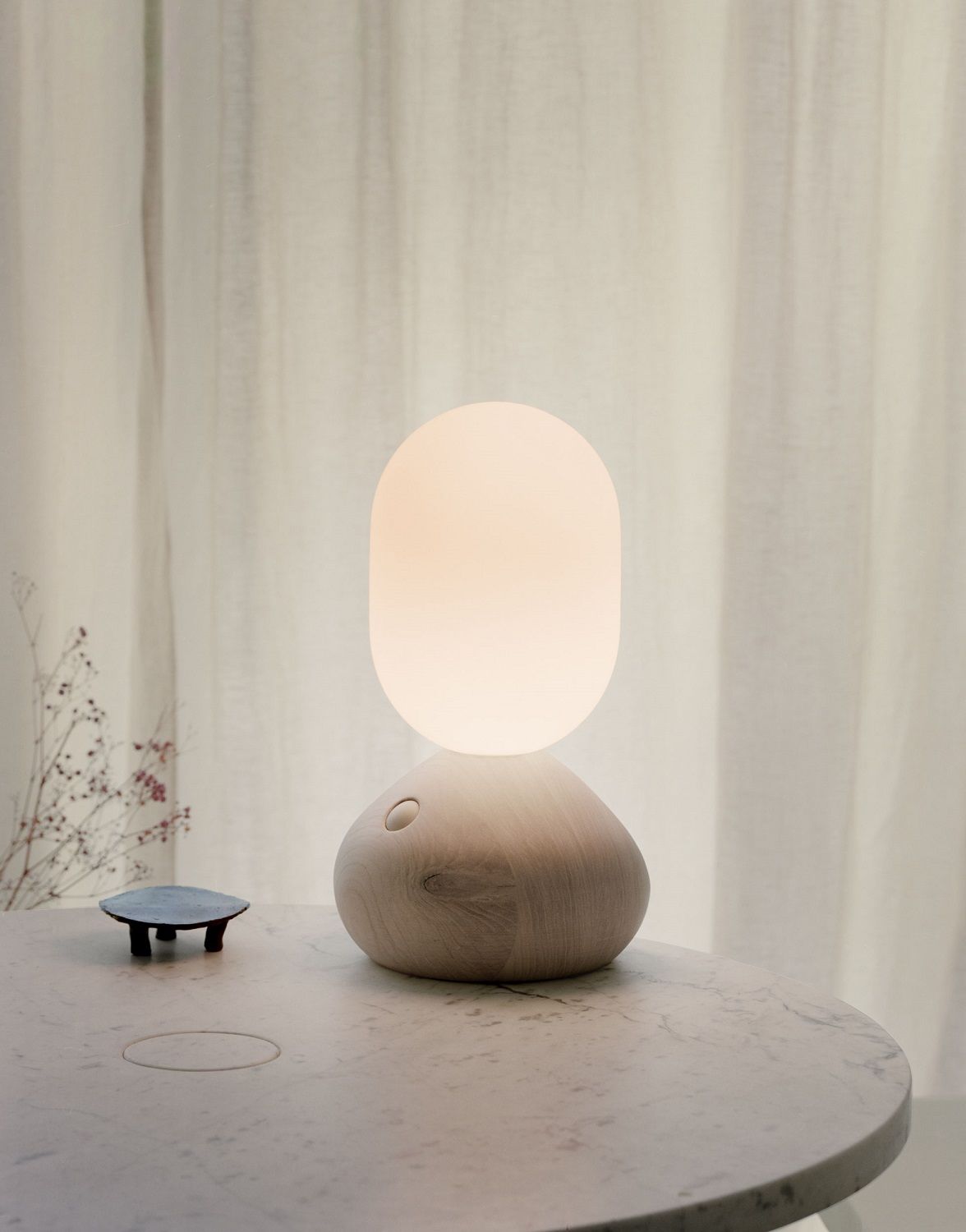 Sun Home Lichtskulptur Tischleuchte in Grau aus Holz und Glas auf einem Marmortisch.