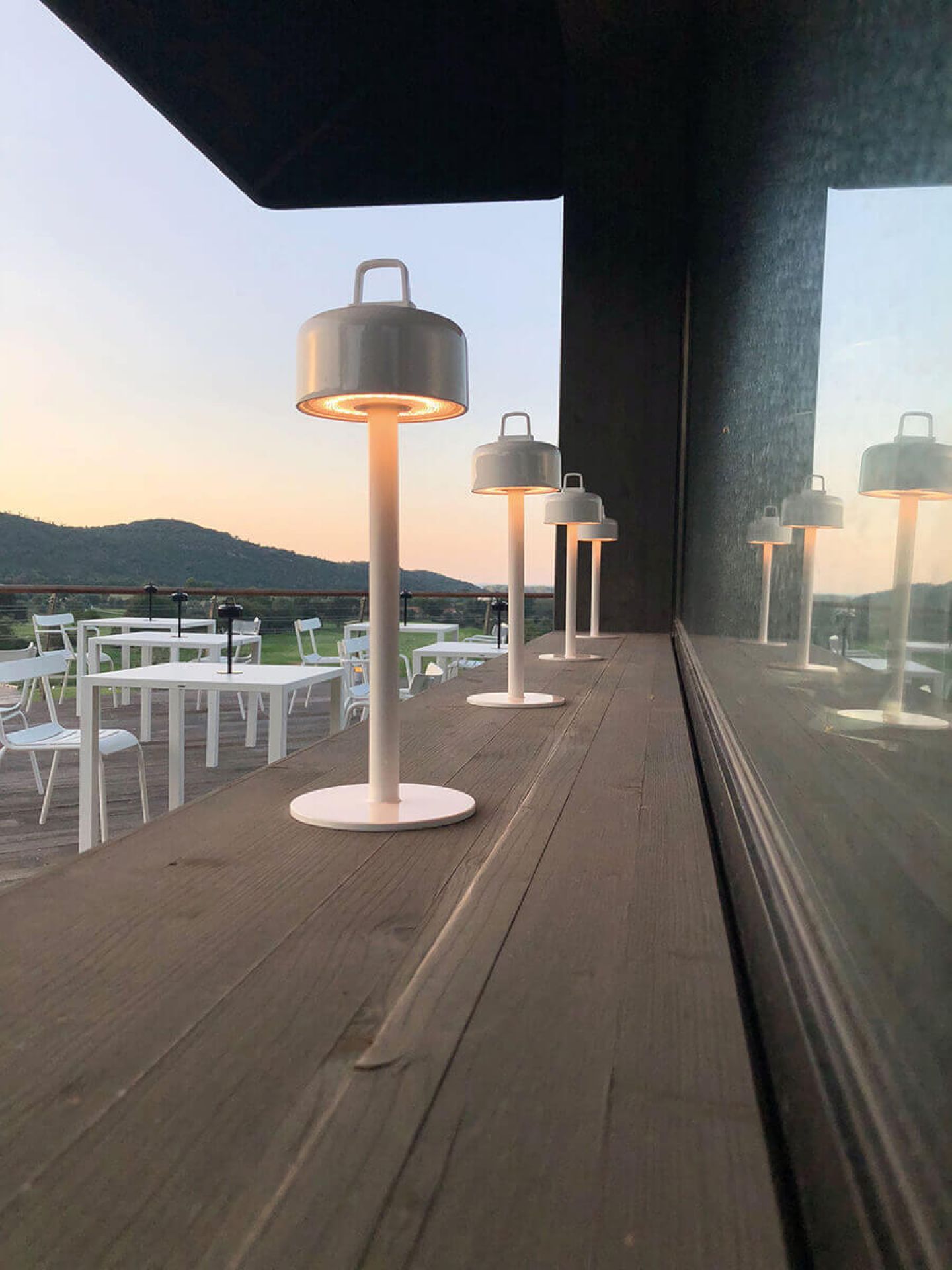 Reihe von Luciole Outdoor Leuchten von Emu auf einer Terrasse bei Sonnenuntergang.