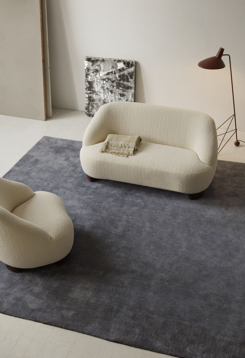 Margas Loungesessel von AndTradition, cremefarben, Bouclé-Bezug, auf grauem Teppich, modernes Wohnzimmer-Interieur.
