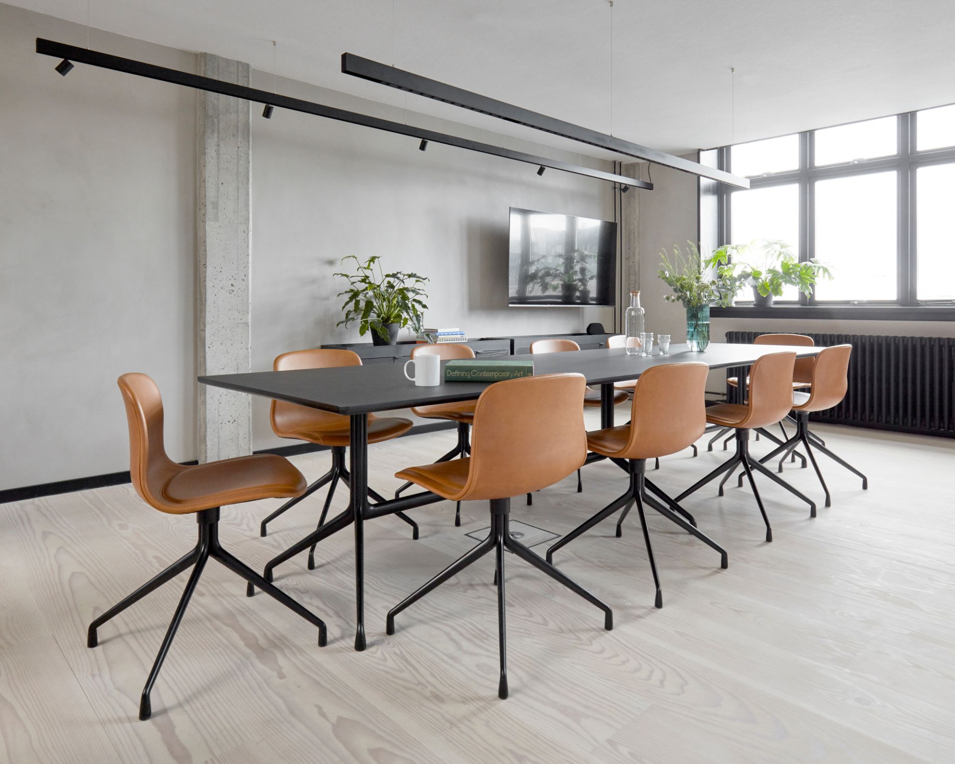 Konferenzraum mit schwarzem Tisch und braunen About a Chair AAC 11 Stühlen mit HALLINGDAL 173 Vollpolsterung.