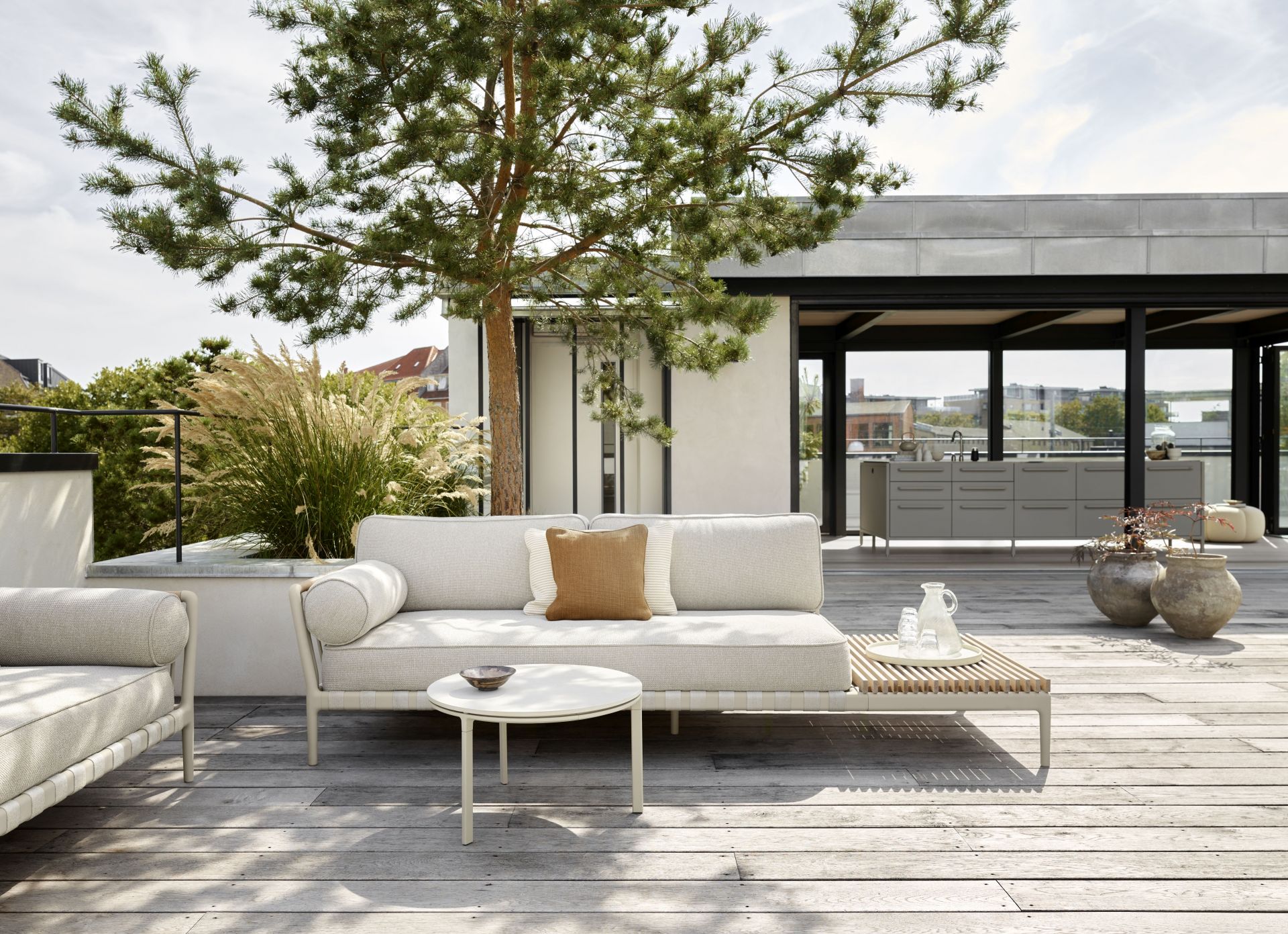 Open-Air Outdoor Lounge mit Vipp Beistelltisch auf einer Dachterrasse mit Holzboden und Stadtblick.