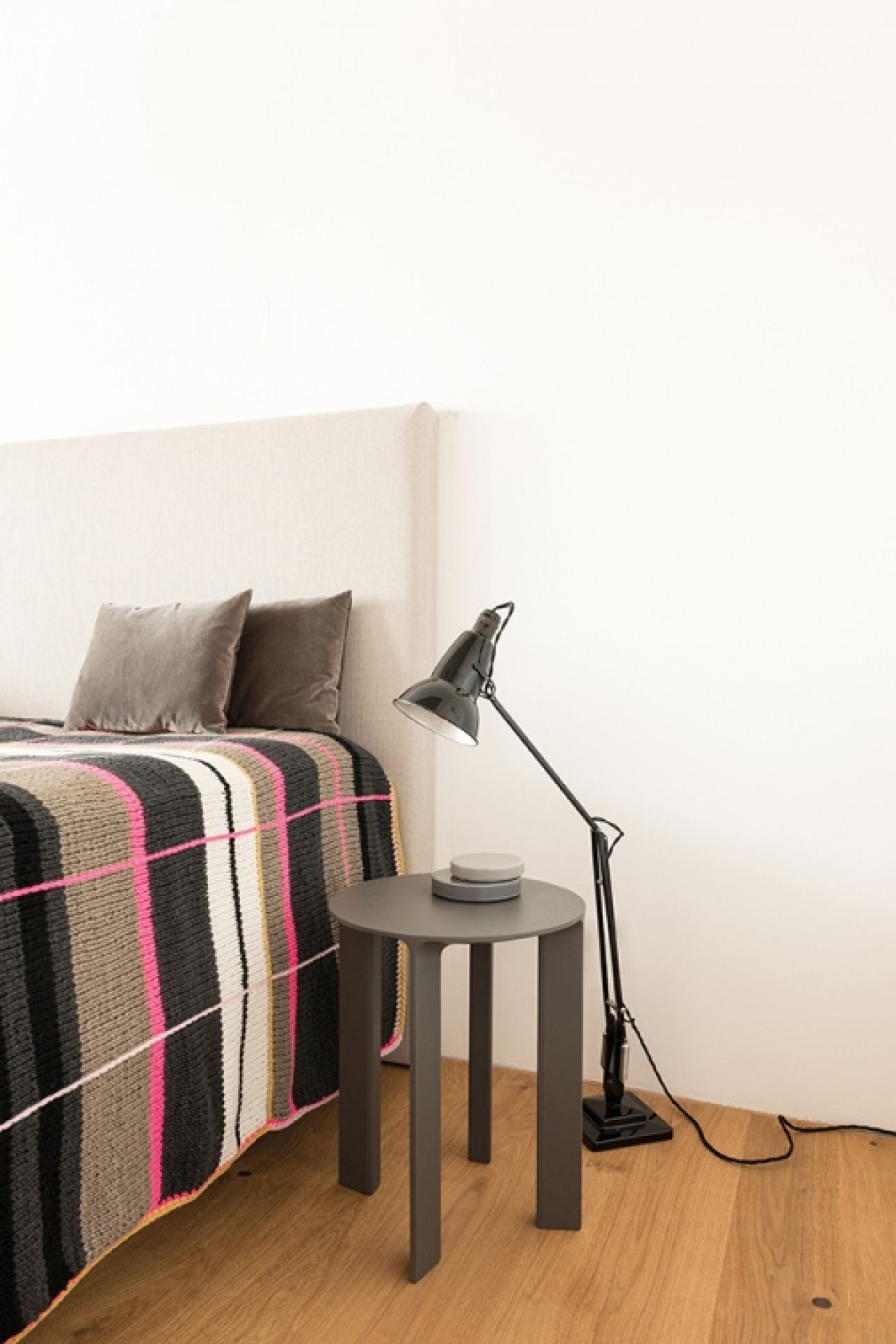 Hans Hocker von Schönbuch, grauer Beistelltisch im Schlafzimmer neben Bett mit Lampe und Deko.