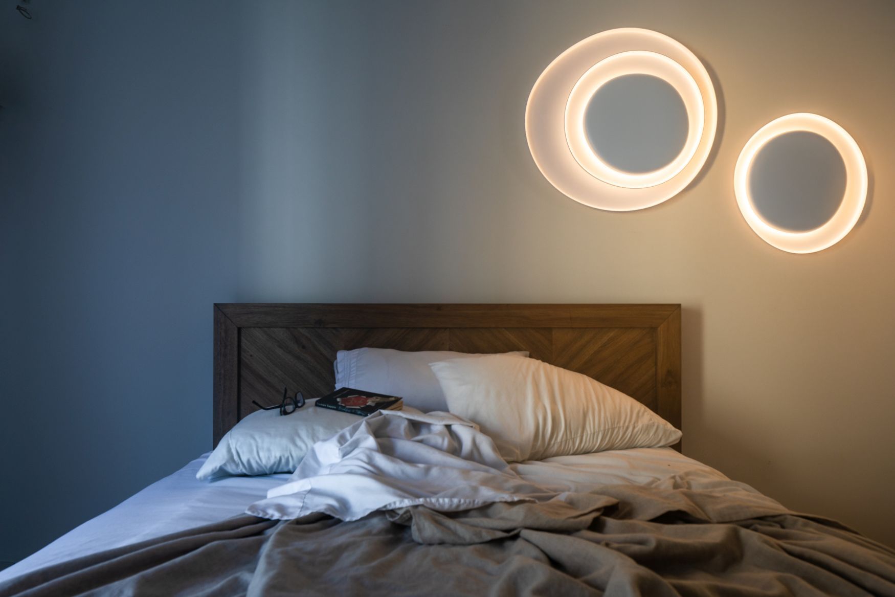 Schlafzimmer mit Bahia Wandleuchten von Foscarini, die ein warmes, indirektes Licht über dem Bett spenden.