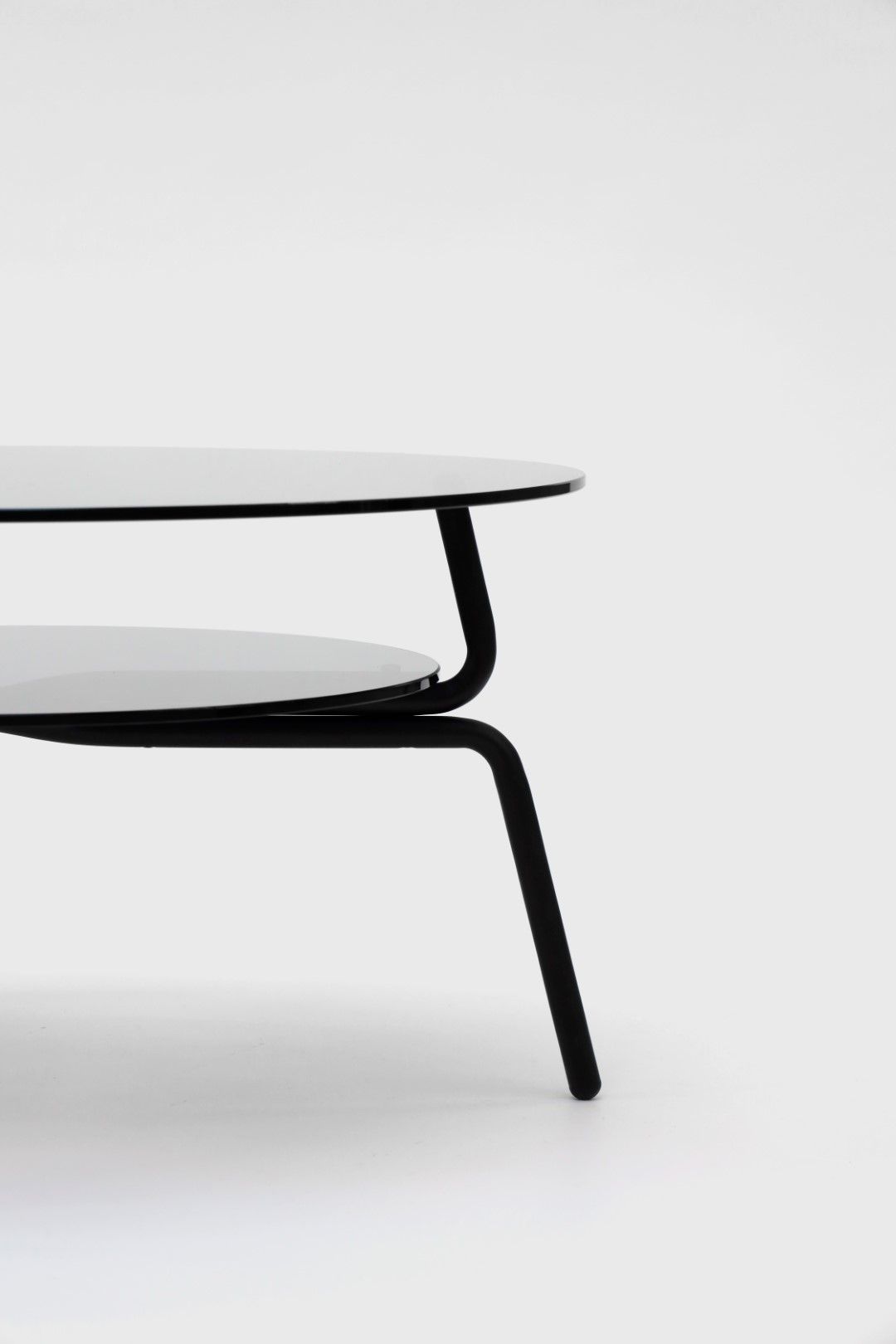 Detailaufnahme des transparenten Lej Couchtisches von Mox mit schwarzem Metallgestell und zwei runden Glasplatten.