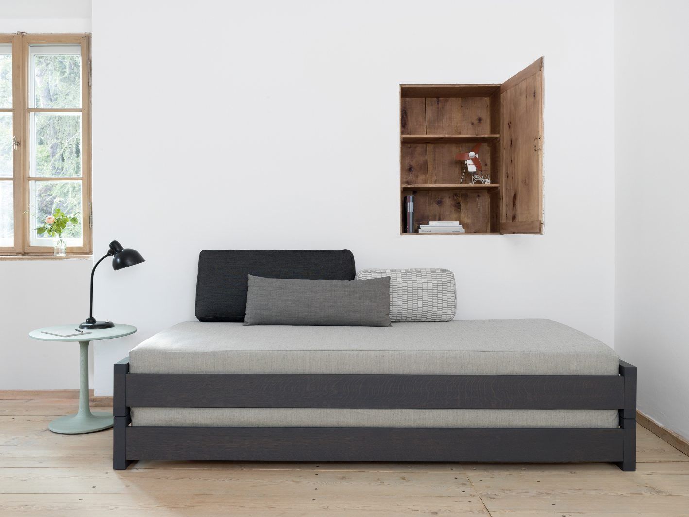 Turntable Couch Beistelltisch Zeitraum: Graues Sofa mit Kissen und kleinem Beistelltisch im minimalistischen Raum.