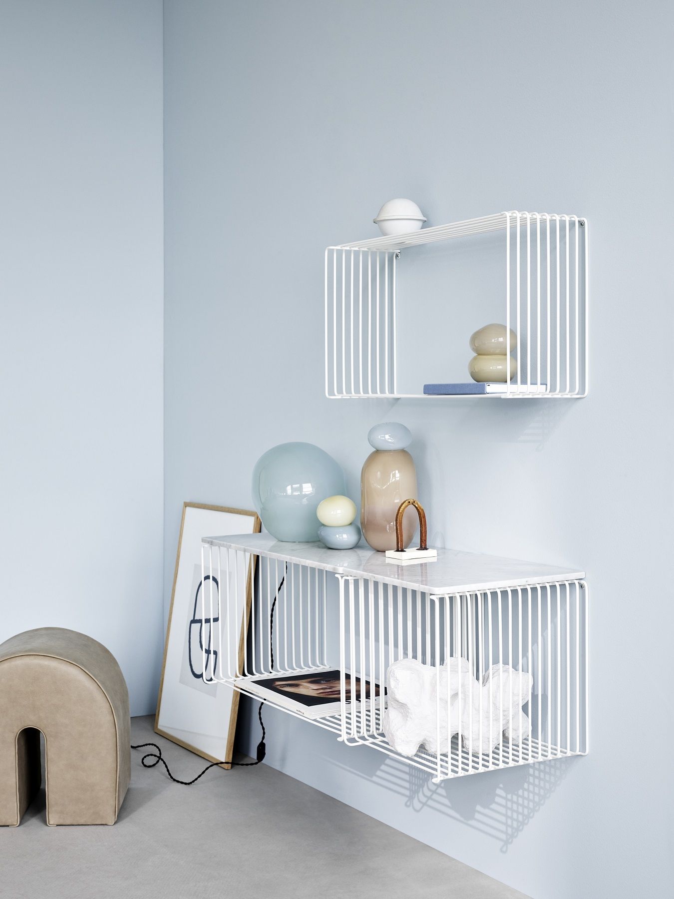 Weißes Panton Wire Regalsystem von Montana, erweiterbar, mit Deko-Objekten an hellblauer Wand.