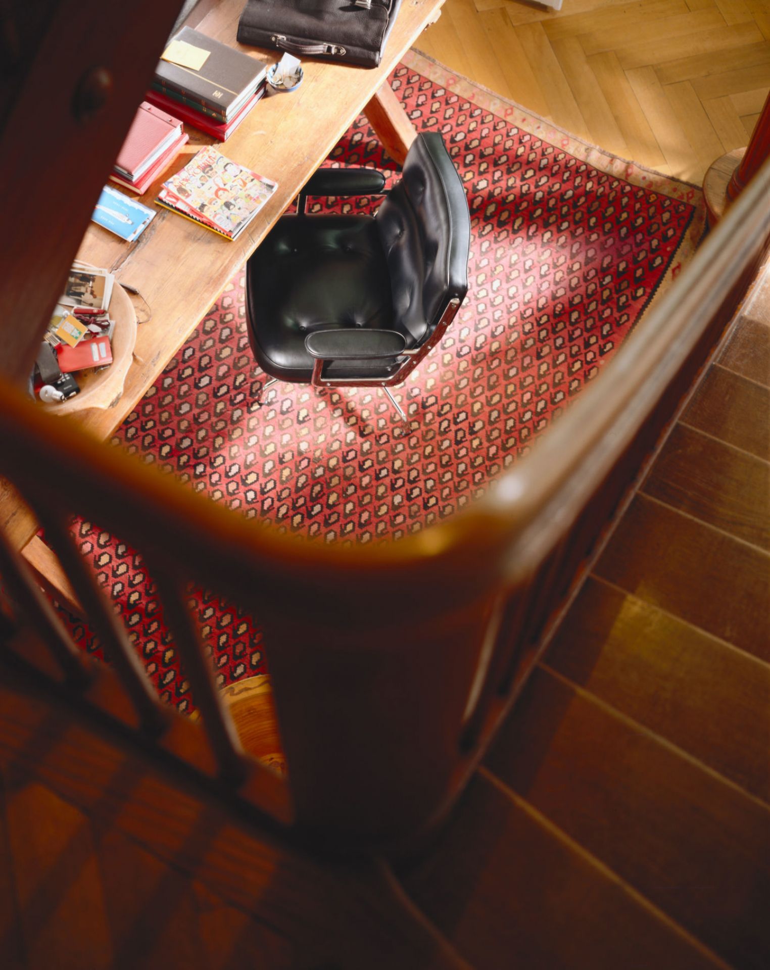 Vogelperspektive des Vitra Lobby Chair ES104 in schwarzem Leder auf einem roten Teppich.