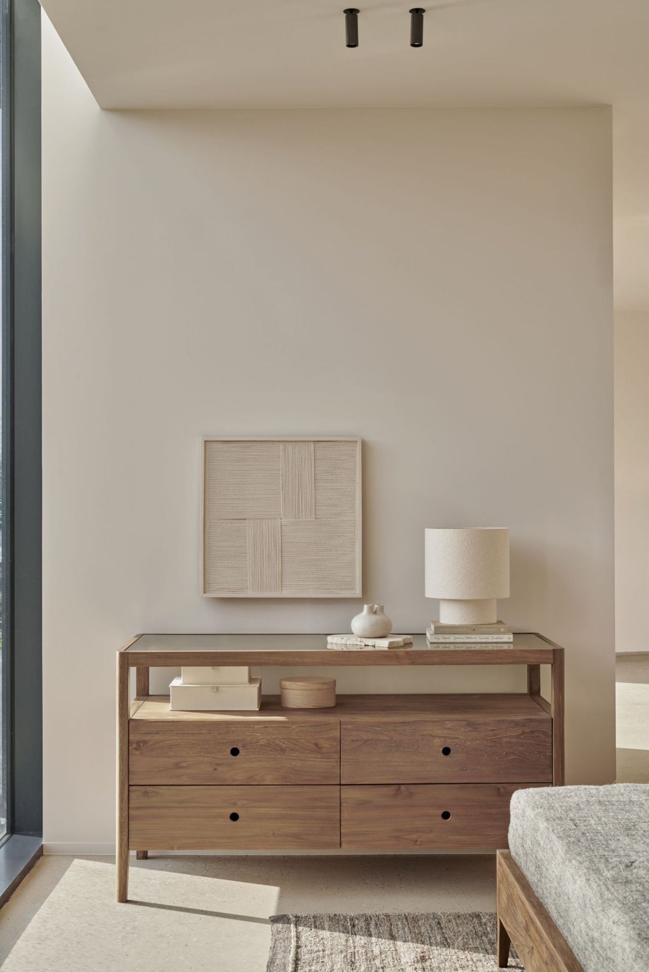 Ethnicraft Spindle Kommode aus Teakholz mit Schubladen, Ablagefläche und dekorativen Accessoires im Wohnzimmer.