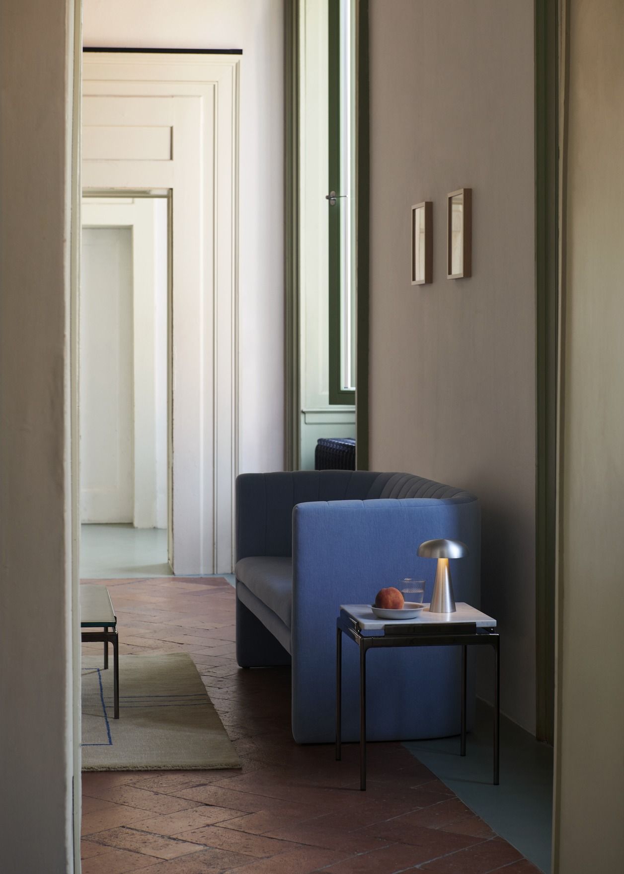 AndTradition Sett LN11 Beistelltisch mit Marmorplatte und Lampe neben blauem Sofa in stilvollem Interieur.
