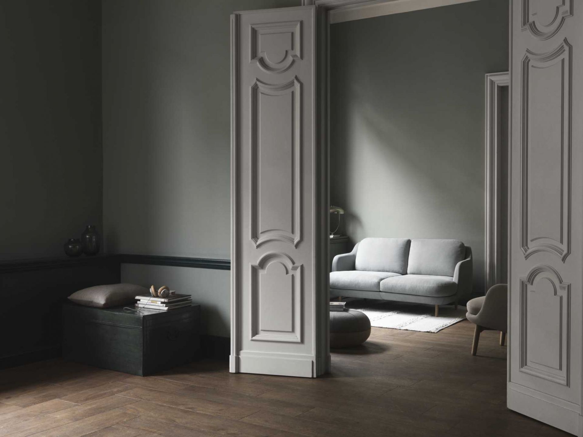 Helles Fritz Hansen Lune Sofa im Wohnzimmer mit grauen Wänden und dunklem Holzboden.