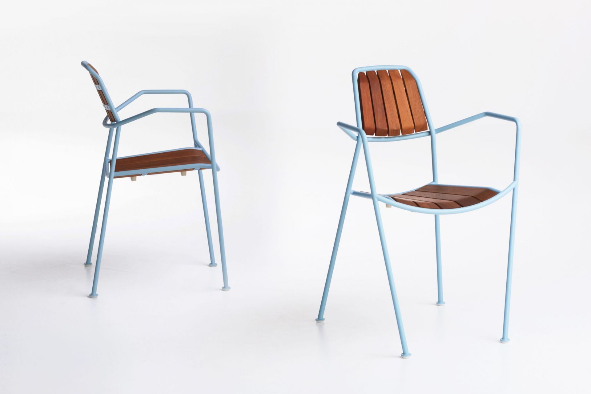 Osmo Stuhl Teak Prostoria: Zwei moderne Armlehnstühle mit hellblauem Metallgestell und Teakholz-Sitzfläche und Rückenlehne.