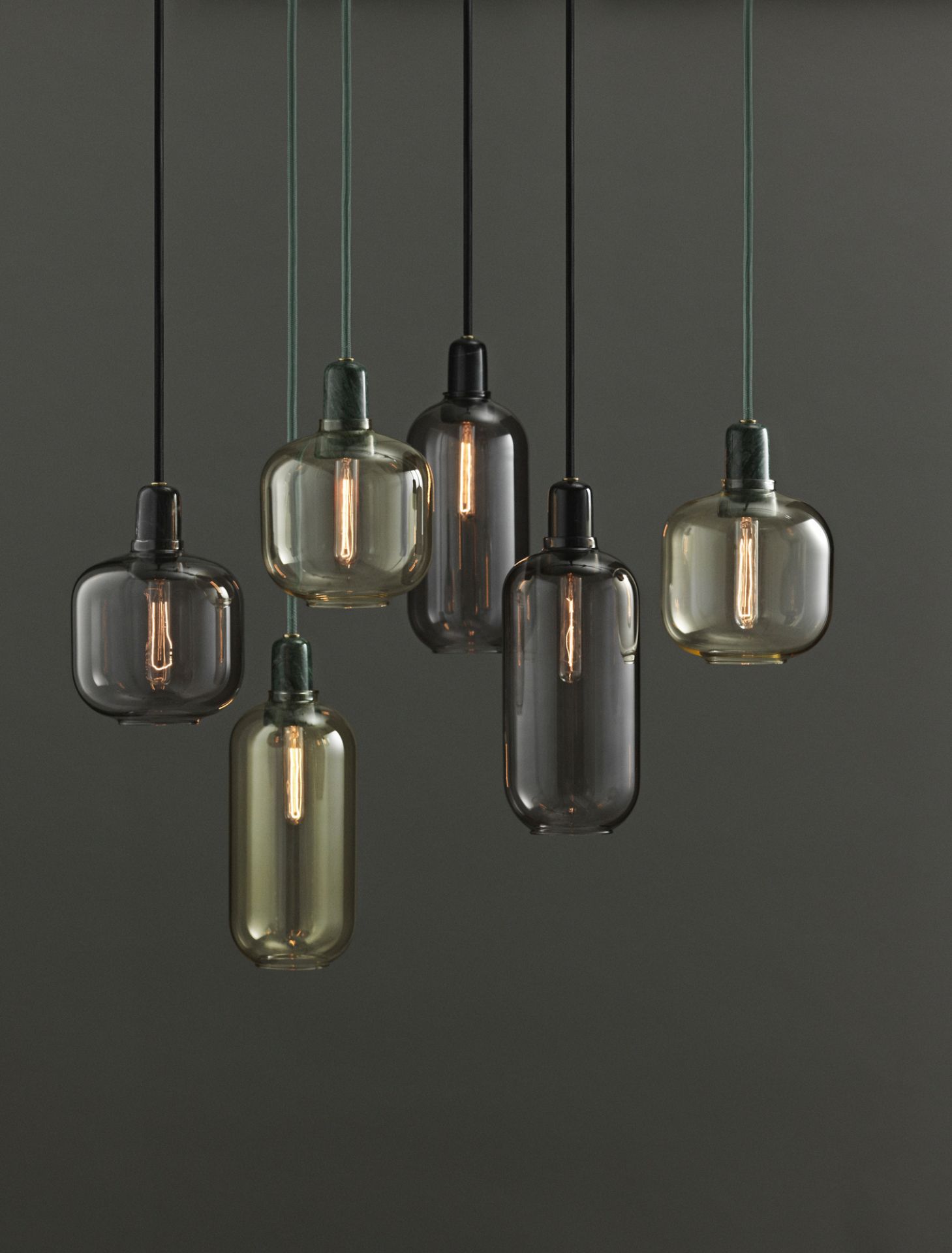 Nahaufnahme von sechs Amp Lamp Hängeleuchten von Normann Copenhagen in Gold und Grün.