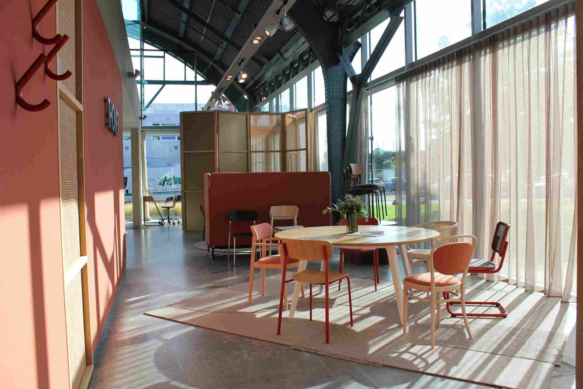 Innenaufnahme mit Thonet S 243 Stahlrohr Stühlen in Olivgrün um einen runden Tisch gruppiert.