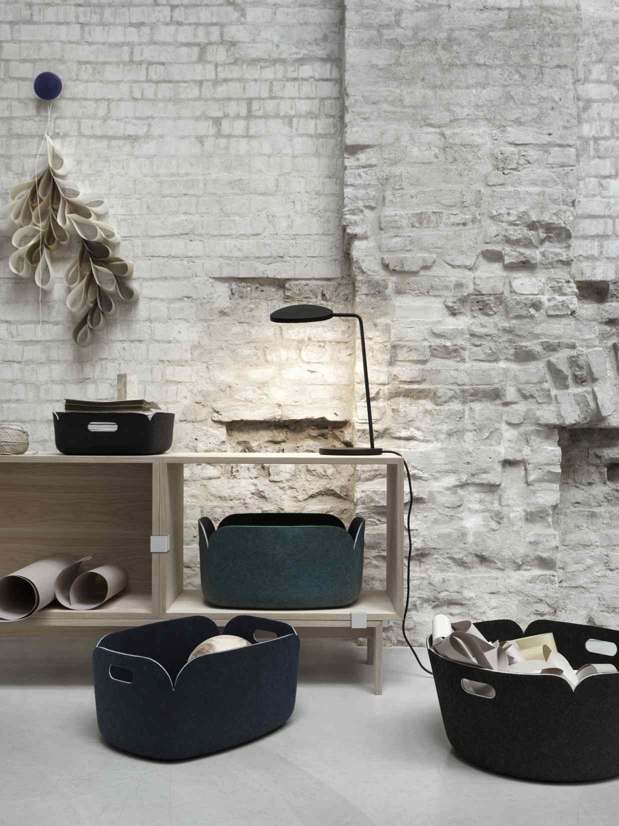 Muuto Stacked Storage System 2.0 Regalsystem mit Aufbewahrungskörben und Lampe vor einer Backsteinwand.
