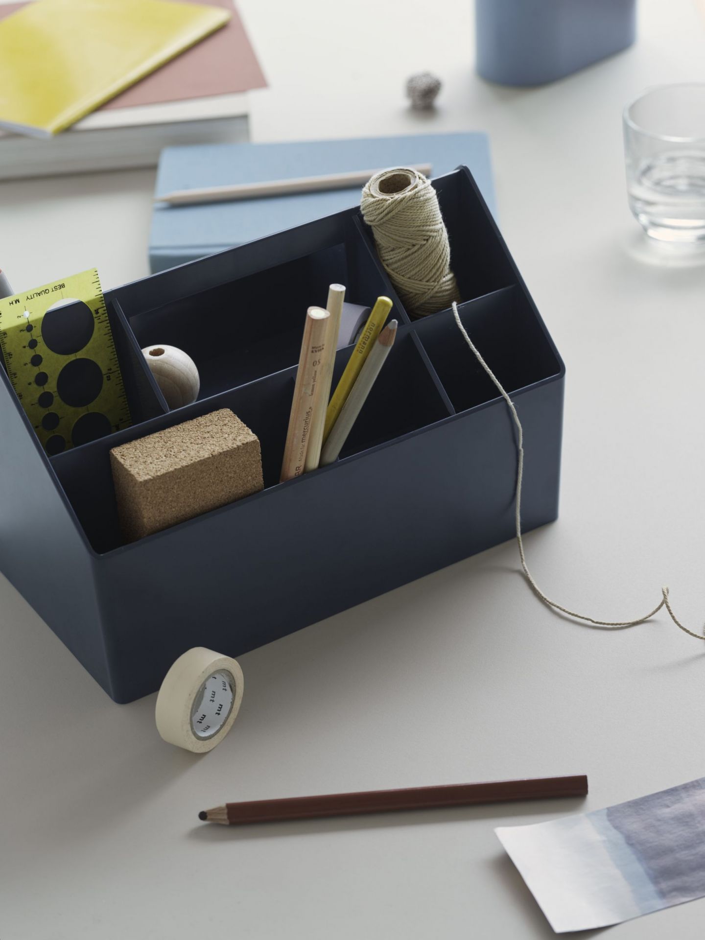 Mitternachtblaue Muuto Sketch Toolbox Organisationsbox mit Stiften, Lineal, Klebeband und Garn auf einem Schreibtisch.